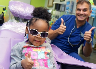 Little girl giving thumbs up in dentist chair